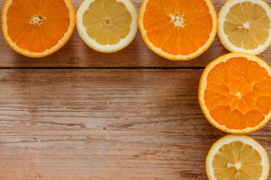 Portakallar, limonlar ve limonlar yukarıdan ahşap masa manzarasına kayar. Taze meyvelerin yarısıyla güzel bir arka plan. Sağlıklı beslenme, vitamin C.Summer tropikal meyve konsepti düzlüğü. Yaratıcı çerçeve