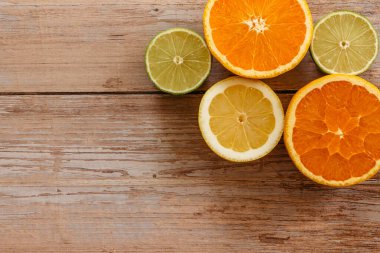 Portakallar, limonlar ve limonlar yukarıdan ahşap masa manzarasına kayar. Taze meyvenin yarısıyla güzel bir arka plan. Sağlıklı beslenen C.Summer vitamini. Tropikal meyve konsepti düzlüğü.
