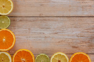 Portakallar, limonlar ve limonlar yukarıdan ahşap masa manzarasına kayar. Taze meyvelerin yarısıyla güzel bir arka plan. Sağlıklı beslenme, vitamin C.Summer tropikal meyve konsepti düzlüğü. Yaratıcı çerçeve.