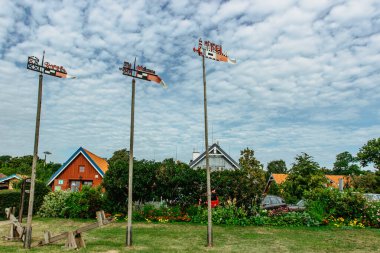 Nida,resort town in Lithuania located on the Curonian Spit. Traditional colorful wooden carved weathercocks typical houses in background.Weather vanes show wind direction and identify fisherman boat. clipart