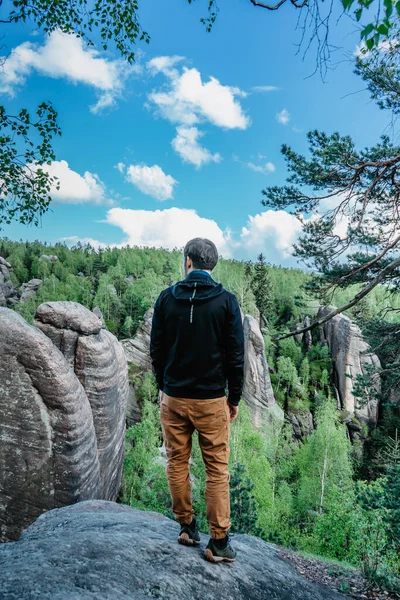 Male traveler standing on rock enjoying views of bizarre sandstone formations called Broumovske steny,Broumov region,Czech Republic.Wanderlust active hiker outdoors.Travel freedom adventure concept.