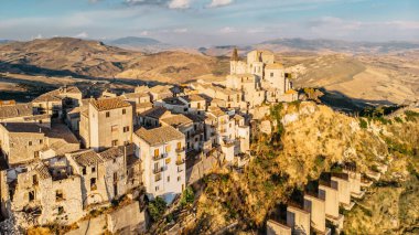 Ortaçağ taş köyünün havadan görünüşü, Madonie dağ sırasının en yüksek köyü, Sicilya, İtalya. Gün batımında Santa Maria di Loreto Kilisesi. Resimli taş evler, dar kaldırımlı sokaklar, kasaba manzarası.