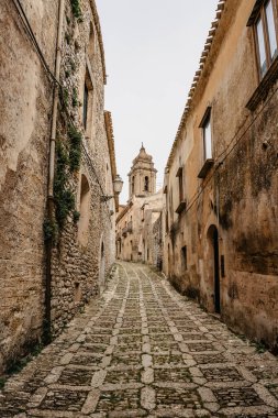 Erice 'de dar bir sokak, San Martino kilise kulesi, Sicilya, İtalya. İtalyan köyünün tarihi merkezi. İnanılmaz ortaçağ Akdeniz taş binaları ve evleri. Popüler turizm merkezi.