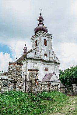 Puste Zibridovice, Çek Cumhuriyeti - 12 Temmuz 2021. Jeseniky dağlarındaki küçük Çek köyünde çan kulesi ve mezarlığı olan eski beyaz barok Saint Mary Kilisesi. Kültür Mirası..