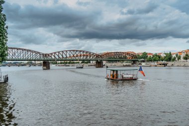 Prag, Çek Cumhuriyeti-4 Ağustos 2021. Çek bayraklı küçük ahşap feribot ve Vltava nehrinden geçen yolcular. Yerel şehir toplu taşımacılığı. Nehir turu, gezme, moda seyahati, eğlenme..