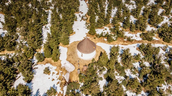 Aerial view of baroque Chapel of the Visitation of Virgin Mary,Kunstat Chapel located in forest of Eagle Mountains,Czech Republic.Circular floor plan and roof covered with shingles.Sunny spring day.