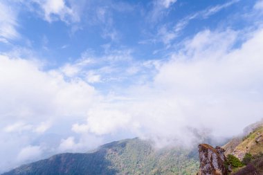 Bahar mevsiminde bulutlar ve gökyüzü ile dağın tepesinden doğayı kucaklamak