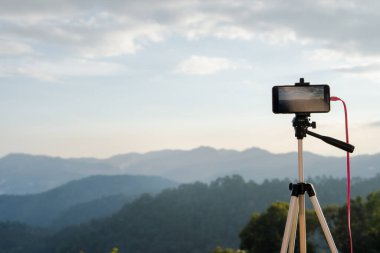 yumuşak odaklı dağ ve tropikal ağaç arkaplanlı akıllı telefonla fotoğraf çek