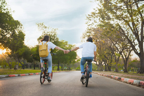 spring is comming concept with happy and cheerful feeling of asian couple riding bicycle together