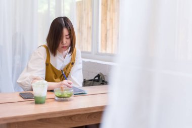 Asyalı serbest kadın, kafeteryadaki internet işi için dijital tablet kullanıyor