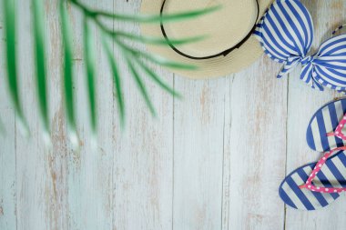 Web afişi ve düz bir yaz mevsimi mayolu ve plaj aksesuarlı klasik mavi ahşap arka planda.