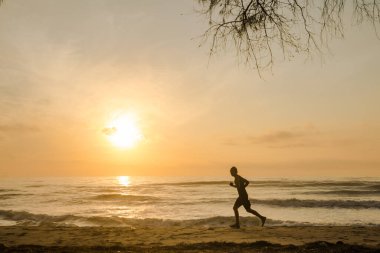 Sahilde koşan siluet adam gün doğumu ve deniz altyapısı ile
