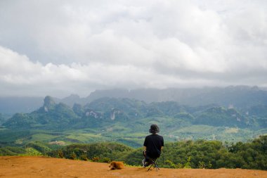 Tek başına yürüyüş yapan adam köpeğiyle dağın tepesinde rahatlar.