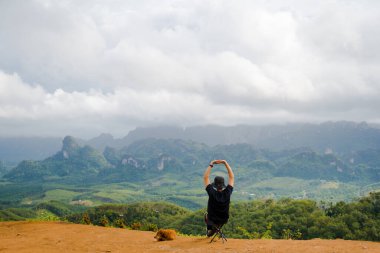 Tek başına yürüyüş yapan adam köpeğiyle dağın tepesinde rahatlar.