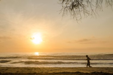 Sahilde koşan siluet adam gün doğumu ve deniz altyapısı ile