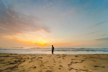 Sahildeki siluet kamp çadırında insanlar güneşin doğuşunu ve deniz altyapısını görüyorlar.