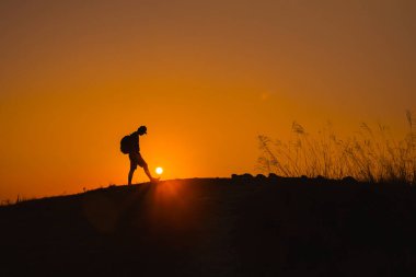 Silüet adamdan yaz mevsiminde dağ başında yürüyüş yapan bir maceraya.