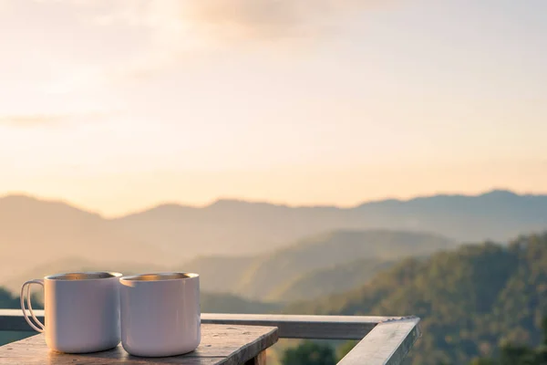 朝の日差しと山の背景のある木のテーブルの上にコーヒーカップ2個 — ストック写真