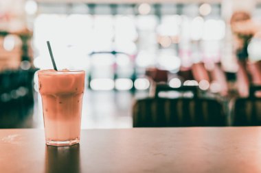 yumuşak odaklı kahve dükkanının arka planında, ahşap bar üzerinde buzlu latte kahve ve kek.