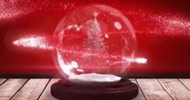Kar küresindeki Noel ağacının kırmızı arka plandaki ahşap yüzeyde canlandırılması. Noel kutlaması konsepti dijital olarak oluşturulmuş görüntü.