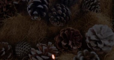 Arka planda çam kozalakları olan mum ve noel süslerinin animasyonu. Noel mevsimleri şenlik kutlaması konsepti dijital olarak oluşturuldu