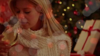 Şarap içen bir kadının üzerine yanıp sönen yılbaşı ışıklarının animasyonu. Koronavirüs salgını sırasında dijital ortamda üretilen kişisel izolasyon noel kutlaması.