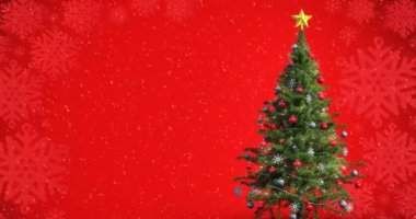 Kırmızı arka planda kar yağan Noel ağacının animasyonu. Noel kutlaması konsepti dijital olarak oluşturulmuş görüntü.