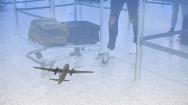 Havaalanında kuyrukta bekleyen yolcuların üzerinden uçan uçak animasyonu. Havaalanında yürüyen yolcuların alçaktan uçtuğu bir uçak.