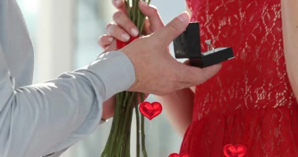 赤いバラを持つ男の上に浮かぶ複数の赤いハートバルーンのアニメーションと女性の指にリングを置く ハッピーバレンタインデーのお祝いのコンセプトデジタル生成された画像 — ストック動画