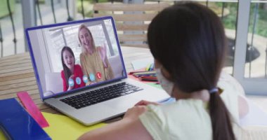 Evde yüz maskesi takan beyaz bir kız var. Coronavirus covid 19 salgını sırasında aile ve arkadaşlarla olan sosyal uzaklık bağlantısı ve iletişimi.