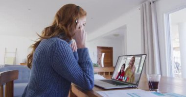 Laptop görüntülü beyaz kadın evde telefon kulaklığı takıyor. Coronavirus covid 19 salgını sırasında aile ve arkadaşlarla olan sosyal uzaklık bağlantısı ve iletişimi.