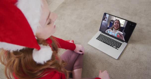 クリスマスに自宅でノートパソコンのビデオ通話でサンタの帽子をかぶった白人女性 19大流行期のクリスマスに友人や家族とのコミュニケーションは — ストック動画