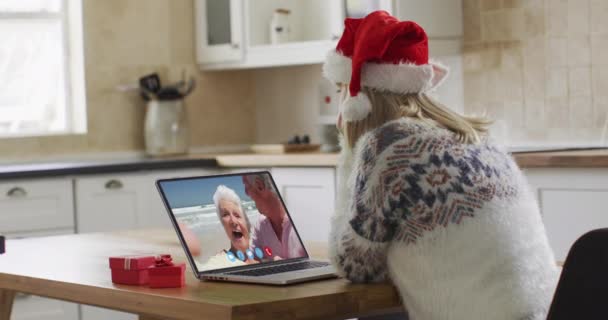 圣诞节期间 白人妇女带着圣诞帽在家里用笔记本电脑进行视频聊天 科罗纳韦病毒大流行期间 圣诞节期间与朋友和家人的沟通 — 图库视频影像