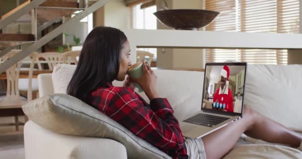 混合种族女性在笔记本电脑视频聊天在圣诞节期间在家喝咖啡 在圣诞节期间与朋友和家人的交流 — 图库视频影像