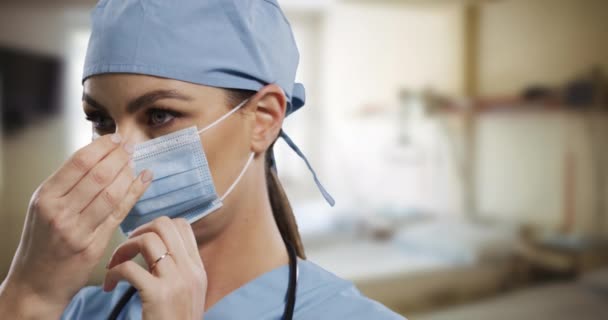 女性の白人外科医は病院で顔のマスクを調整している コロナウイルス中の病院での衛生と感染予防 Covid 19パンデミック — ストック動画