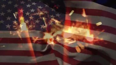 Amerikan bayrağının dalgalanmasına karşı havai fişeklerin yakın plan çekimi. Vatanseverlik yıldızları ve çizgiler konsepti dijital olarak oluşturuldu.