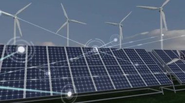 Güneş panellerine karşı kurulan bağlantılar ve mavi gökyüzüne karşı dönen çoklu yel değirmeni ağı. yenilenebilir enerji koruma kavramı