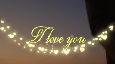 I Love You 'nun animasyonu. Bir dizi peri ışığı ve birbirine aşık çiftlerin yaz aylarında arka planda koşan el ele tutuşmalarıyla yazılmış. Sevgililer Günü kutlaması konsepti dijital bileşik.