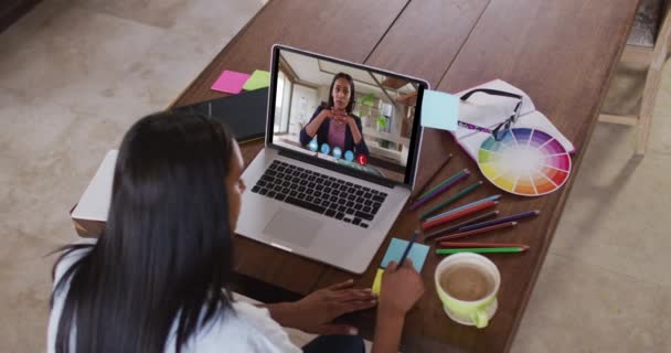 女性の同僚とビデオ通話でラップトップを使用し 自宅からノートを作る白人女性 隔離されたまま家にいると — ストック動画