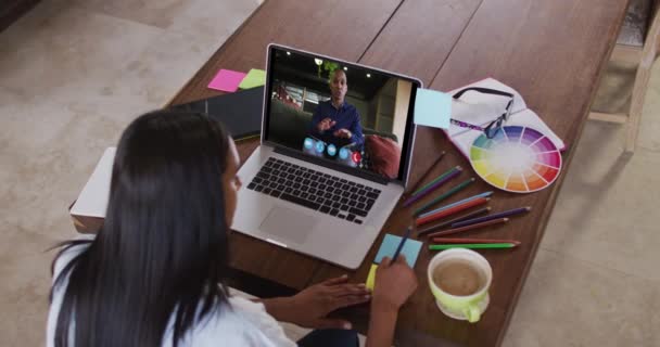 여성이 동료와 비디오 통화로 노트북을 사용하고 집에서 일하는 노트를 만들고 — 비디오