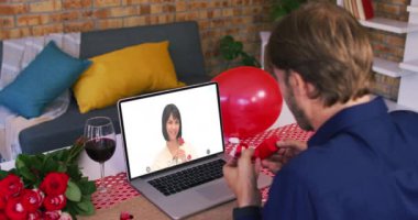 Sevgililer gününde çeşitli çiftler dizüstü bilgisayar ekranında gülümseyen kadına yüzük gösteren bir videocu adamla çıkıyorlar.