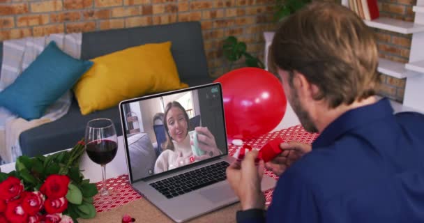 Caucásico pareja en una fecha de San Valentín videollamada hombre mostrando anillo a la mujer sonriente en la pantalla del ordenador portátil — Vídeos de Stock