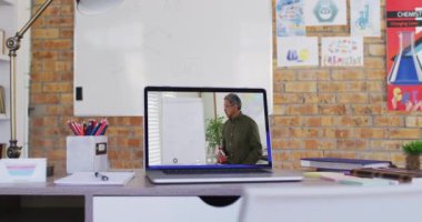 Video çağrısında karışık ırk erkek öğretmeni dizüstü bilgisayarda görüntülendi. Çevrimiçi eğitim karantina süresince evde tek başına kalıyor..