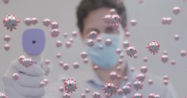 Dijital termometre tutan yüz maskesi takan adamın üzerinde süzülen kovid 19 hücrenin animasyonu. Coronavirus covid 19 salgını sırasında sağlık ve korunma, dijital olarak üretilen video.