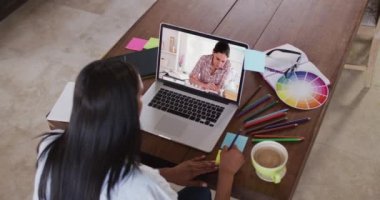Beyaz kadın öğretmen kız öğrenciyle video görüşmesinde dizüstü bilgisayar kullanıyor, notlar alıyor. Çevrimiçi eğitim karantina süresince evde tek başına kalıyor..