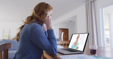 Beyaz bir kadın, bayan meslektaşıyla konuşurken bilgisayar ve kulaklık kullanıyor. Karantina süresince evde tek başına kalmak..