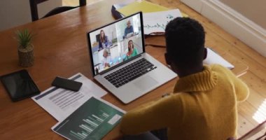 Afrikalı Amerikalı bir kadın bilgisayarla evden iş arkadaşlarıyla görüntülü görüşme yapıyor. Karantina süresince evde tek başına kalmak..