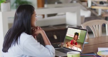 Beyaz kadın öğretmen, liseli kızla video görüşmesinde dizüstü bilgisayar kullanıyor. Çevrimiçi eğitim karantina süresince evde tek başına kalıyor..