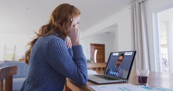白人妇女使用笔记本电脑和手机耳机与男性同事进行视频通话 隔离隔离期间在家中自我隔离 — 图库视频影像