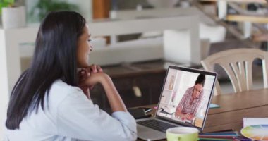 Beyaz kadın öğretmen, kız öğrenciyle video görüşmesinde dizüstü bilgisayar kullanıyor. Çevrimiçi eğitim karantina süresince evde tek başına kalıyor..